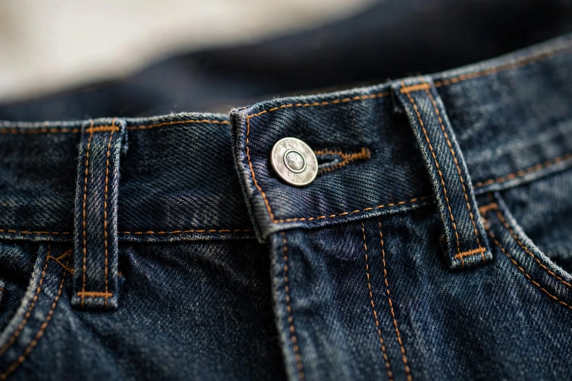 Close-up of high-rise jeans waistband and button detail