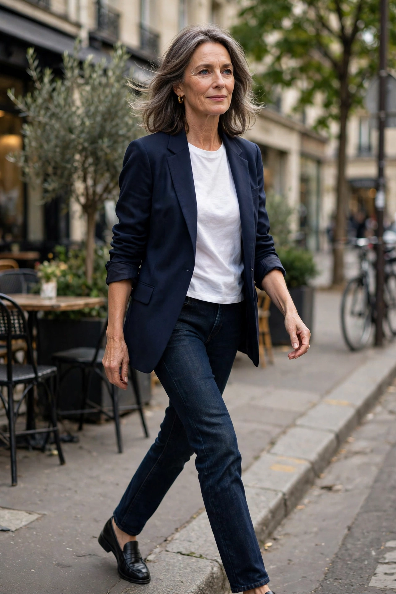 Woman in her late 50s in a navy blazer, white t-shirt, dark jeans and loafers