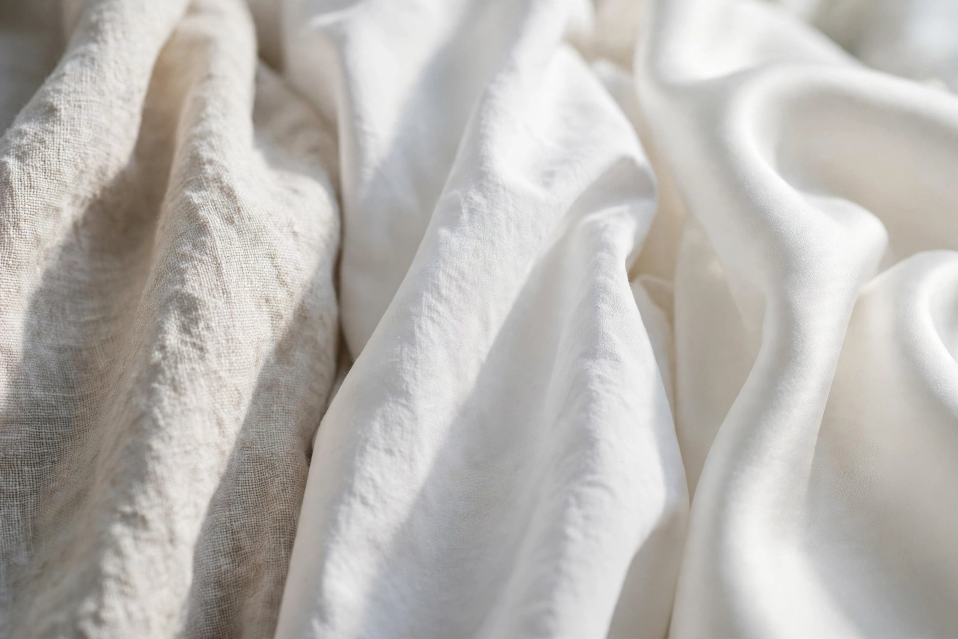 Close-up of elegant white fabric textures — linen, cotton poplin and silk