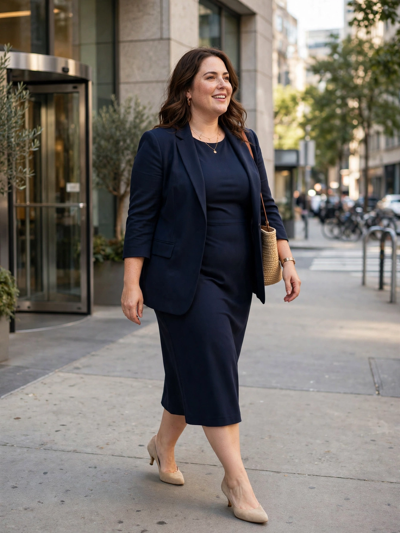 Plus-size woman in a navy sheath midi dress with matching blazer and beige pumps